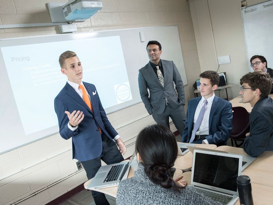 Aluno do Upper School de terno fazendo uma apresentação para os colegas
