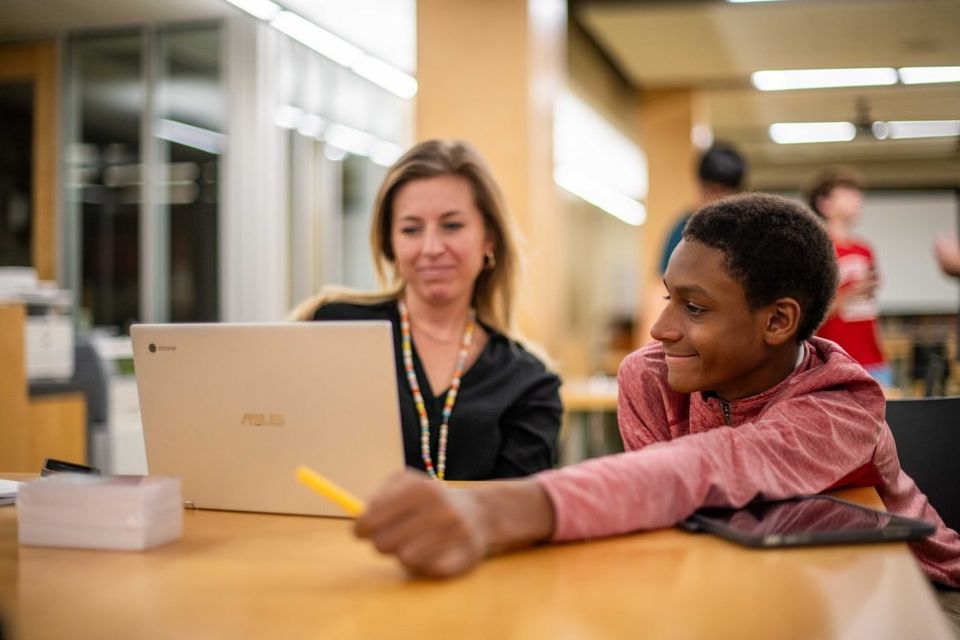 Interno trabalhando em um Chromebook com um funcionário durante o estudo noturno