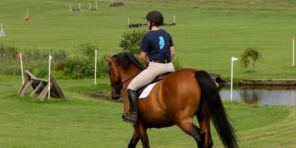 Aluna cavalgando no campo de cross-country