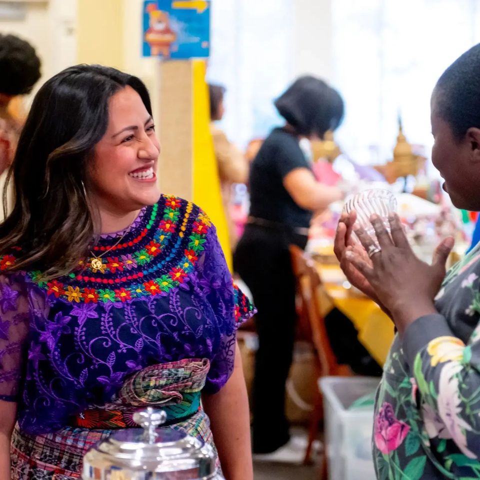Mulher em traje tradicional guatemalteco em evento cultural no campus, com alunos