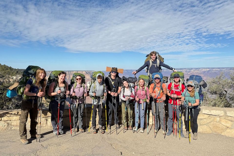 Alunos com mochilas enfileirados na borda de um cânion durante uma expedição de campo