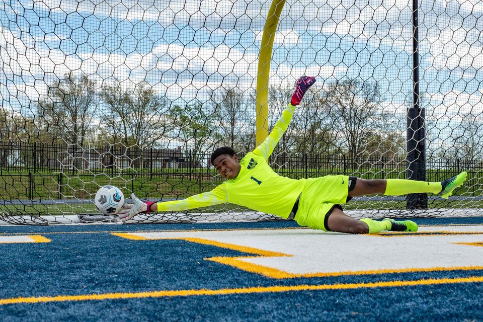 Goleiro do time de futebol do high school saltando para defender um chute