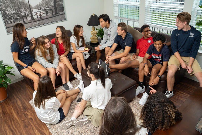 Cerca de doze internos descansando juntos nos sofás da sala de uma townhouse