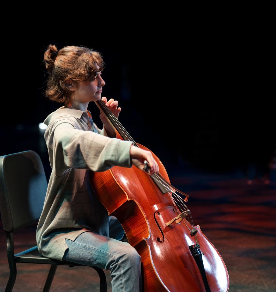 Aluno tocando violoncelo no palco