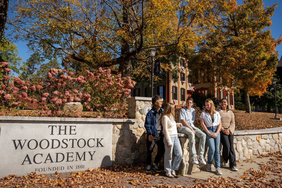 Alunos reunidos junto à placa da The Woodstock Academy no outono