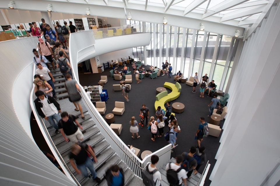 Estudantes na área de estudo do terceiro andar da Jack R. Hunt Library, dentro do Student Union da Embry-Riddle em Daytona Beach, com escada curva e clarabóia