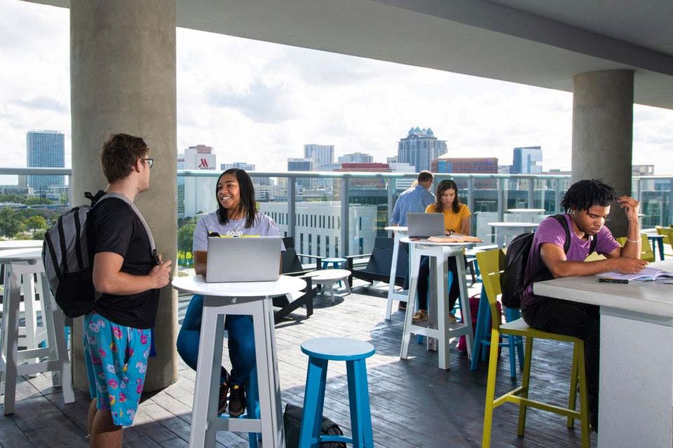 Estudantes estudando no terraço do UnionWest com o skyline do centro de Orlando ao fundo